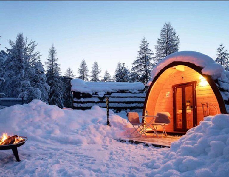 Beleuchteter Camping-Pod im Schnee mit Feuerschale