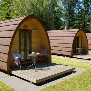 Zwei Camping-Pods mit Rundbogendach und Terrasse auf einer Wiese